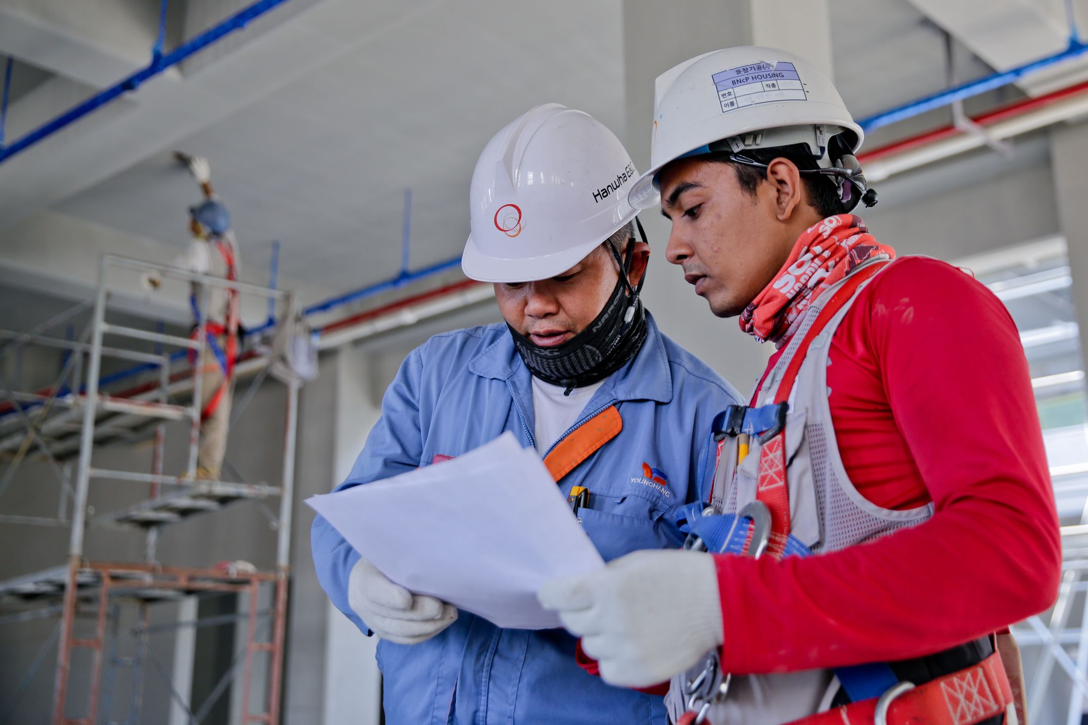 Two builders in hard hats reading a drawing set on an active jobsite